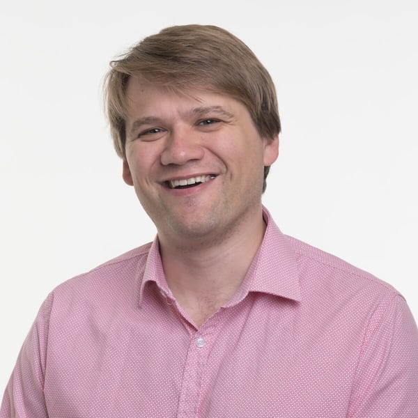 A picture of smiling Henri Hämäläinen, Eficode's head of advisory services, in a light pink collar shirt against a white background.